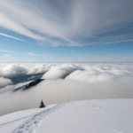 Stunning view of a snowy mountain peak with clouds swirling around it, embodying the awe of nature's majesty.
