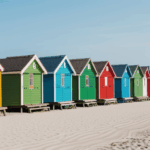 Sunny beach day with colorful beach huts lining the sandy shore