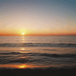 A calm ocean at sunset, with the sky painted in stunning, vibrant hues.