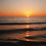 Sunset over ocean waves with the sky ablaze in warm, vibrant hues.