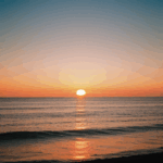 A serene sunset over the water, with the sky painted in warm, vibrant colors.