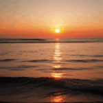 Sunset reflections on water, with the horizon glowing in warm colors.