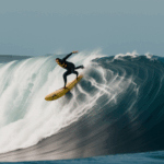 An action shot of a surfer navigating a towering wave, capturing the thrill and excitement of surfing.