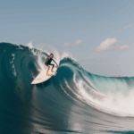 An adventurous surfer navigates a massive wave, capturing the essence of the surfing lifestyle and the thrill of ocean sports.