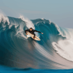 A surfer living their surfing dreams, riding an impressive wave in the open ocean.