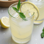 Lemonade with vibrant mint leaves and a glass full of ice.