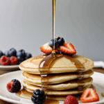 A gourmet stack of pancakes with syrup and a mix of fresh, colorful berries, ideal for a brunch centerpiece.