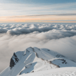 Towering snowy mountain peak piercing through the clouds, illustrating the grandeur of untouched natural wonders.