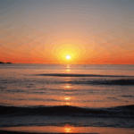 A tranquil evening sunset casting serene hues over the calm ocean horizon.