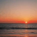 Tranquil ocean sunset with the horizon glowing in warm, vibrant colors.