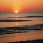 Serene ocean reflecting the stunning colors of a setting sun.
