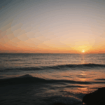 Tranquil ocean views with a stunning sunset in the background, painting the sky.