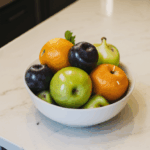 Tropical fruit bowl with an array of vibrant, fresh fruits in a kitchen setting.
