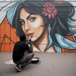 An urban artist in the midst of creating a stunning mural on a city wall.