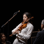 A talented violinist passionately performing on stage, captivating the audience with their skill and emotion.