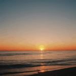 Vivid sunset ocean with the horizon reflecting warm, vibrant colors.
