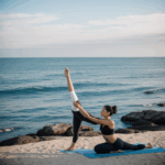 A woman gracefully practicing yoga on a serene beach with the ocean in the background, embodying tranquility and balance.