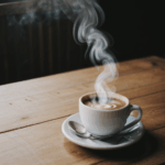A steaming hot cup of coffee, elegantly placed on a wooden table.