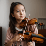 A young girl passionately playing the violin, showcasing her dedication and love for music.