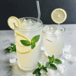 A close-up of a zesty lemon beverage, complete with ice and mint leaves, perfect for a hot day.